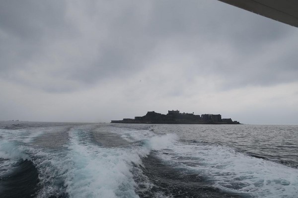 從回程的船尾遠眺軍艦島，黑色剪影讓人彷彿回到電影場景。