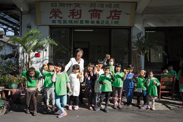 採訪那天，剛好是鎮平國小附設幼兒園的校外教學，看見孩子們來訪，江鳳英先是躲起來，讓他們自己買東西，最後才現身送襪子給孩子。