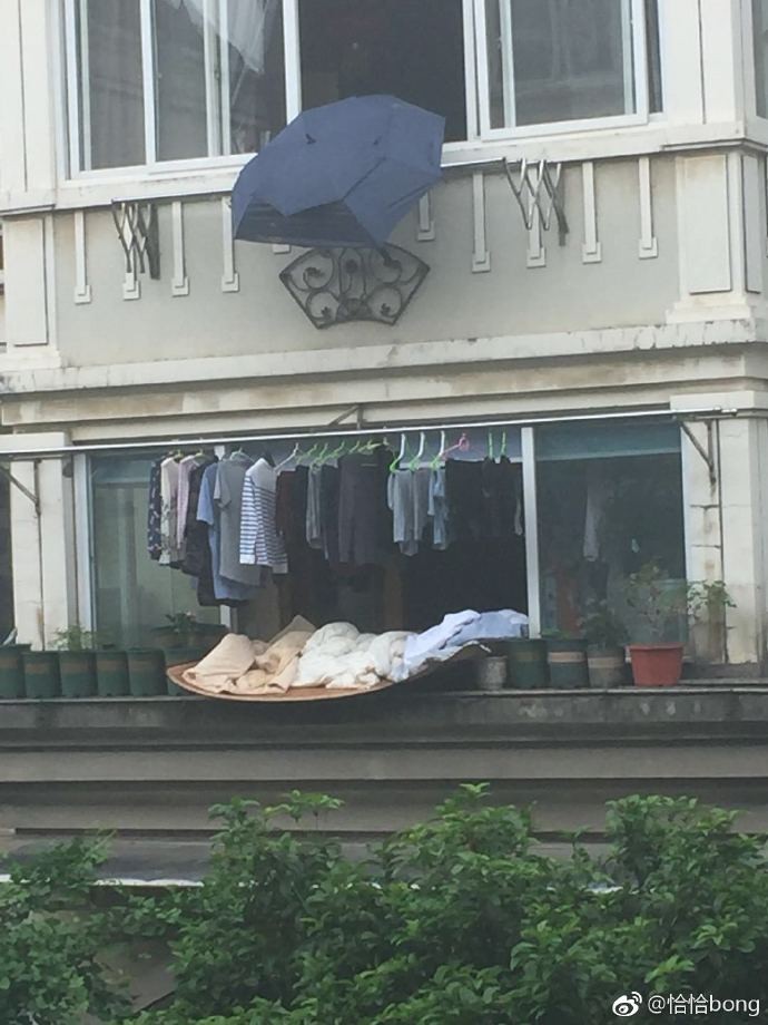 ▲▼浙江寧波一名老翁為樓下鄰居的衣物撐傘。（圖／取自「恰恰bong」微博）