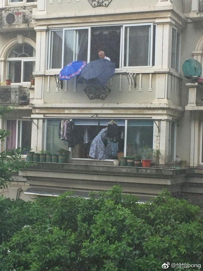 ▲▼浙江寧波一名老翁為樓下鄰居的衣物撐傘。（圖／取自「恰恰bong」微博）