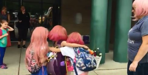 ▲ 「粉紅假髮日」當天，艾莉看見大家都頂著一樣的髮色，與朋友們喜悅的擁抱 。（圖／翻攝自Katie Thompson推特）