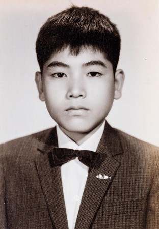 還是小學時期的吳文耀，胸前別著父親打製的黃金布丁胸針，在相館拍了人生第一張照片。（吳文耀提供）