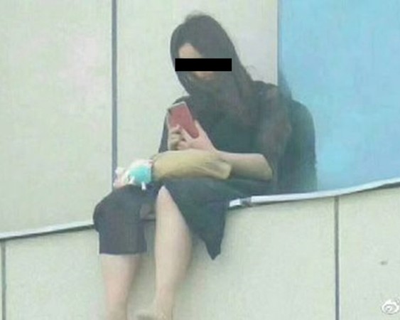 ▲19歲女孩李奕奕坐在飯店窗戶外，企圖跳樓輕生。（圖／翻攝自大陸網站）           