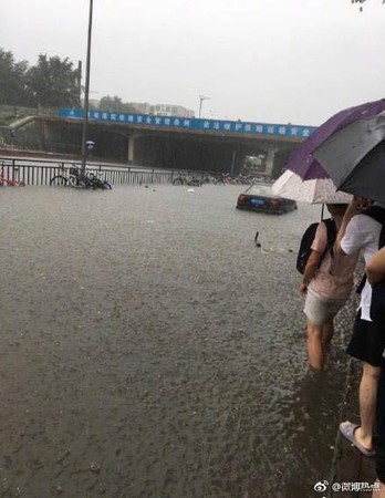 ▲民眾在大雨中涉水而過。（圖／翻攝自微博）