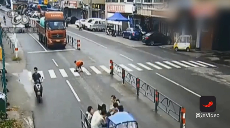 ▲中國江蘇無錫一名女路人前往救狗，被大貨車輾腿。（圖／翻攝自梨視頻）