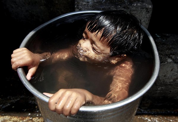 2015年印度出現破紀錄高溫，導致超過2000人死亡。圖中一名孟買小孩泡在水桶裡消除暑氣。（東方IC）