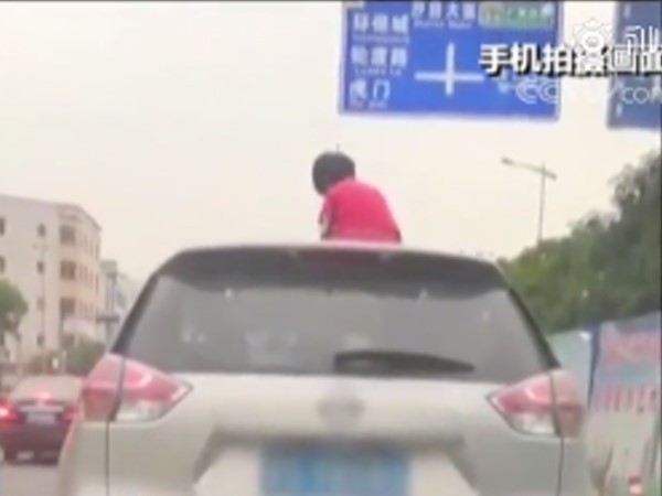 趁老爸忙著開車，女童爬出天窗吹風。（圖／翻攝自微博／央視新聞）