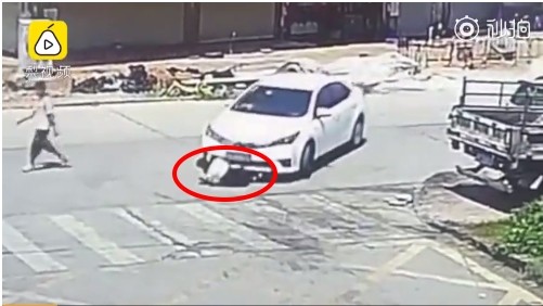 ▲▼廣東珠海一名男子蹲在路口繫鞋帶，被後方轎車輾過。（圖／翻攝畫面）
