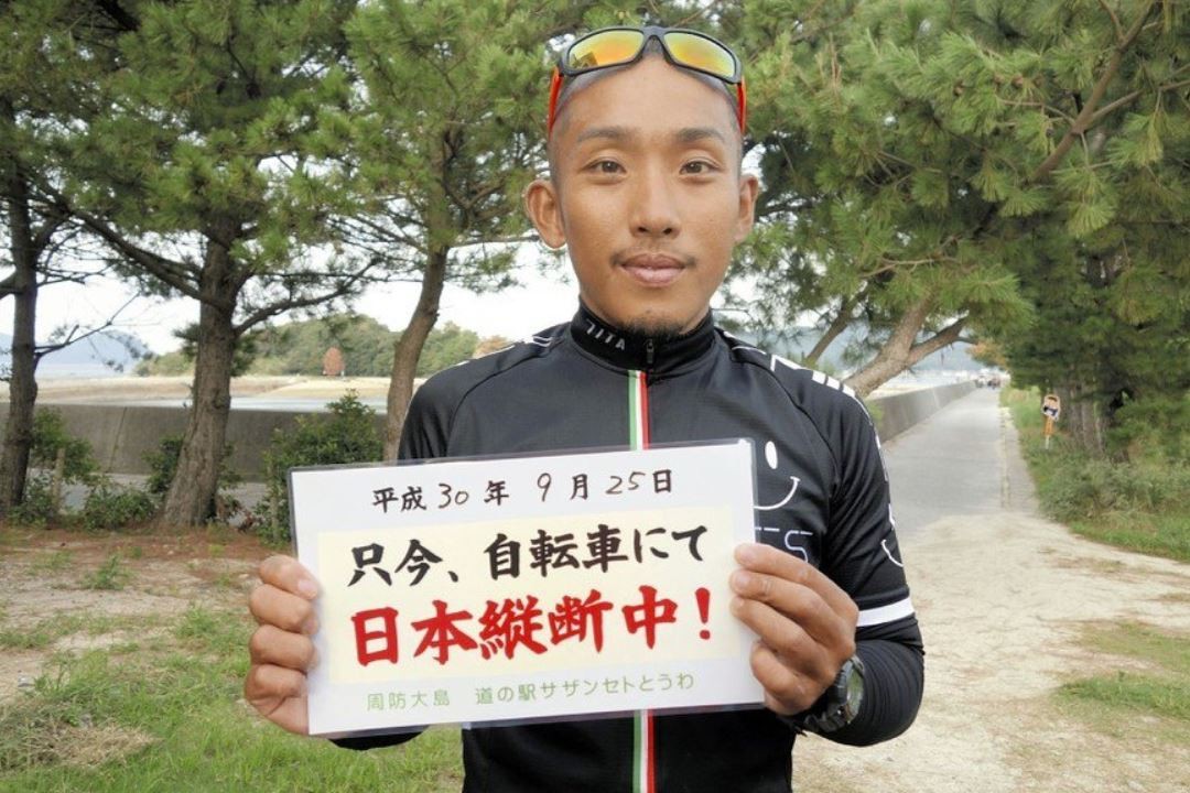 ▲ 樋田淳也舉著「現在騎車挑戰日本環島中！」的板子，臉上看不出任何逃亡的緊張感 。（圖／翻攝自sakamobi推特）