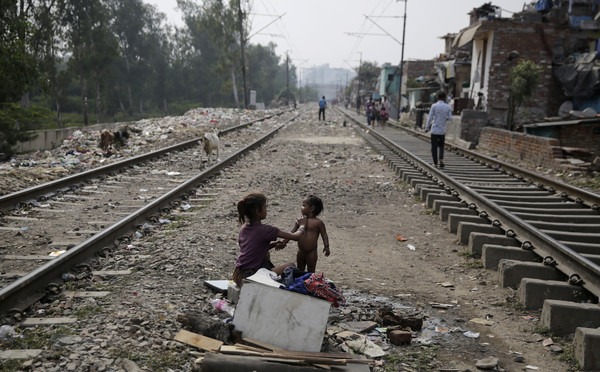 ▲印度新德里一名女孩在鐵路旁替小孩洗澡,貧窮。（圖／路透）