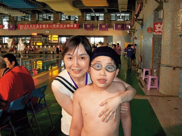 游高晏（右）每週末都會去游泳，晏媽唐雅婷（左）說：「他游了十年，還是沒游很好。」圖為游高晏十二歲參加慧行盃身心障礙者游泳比賽。（游章耀提供）