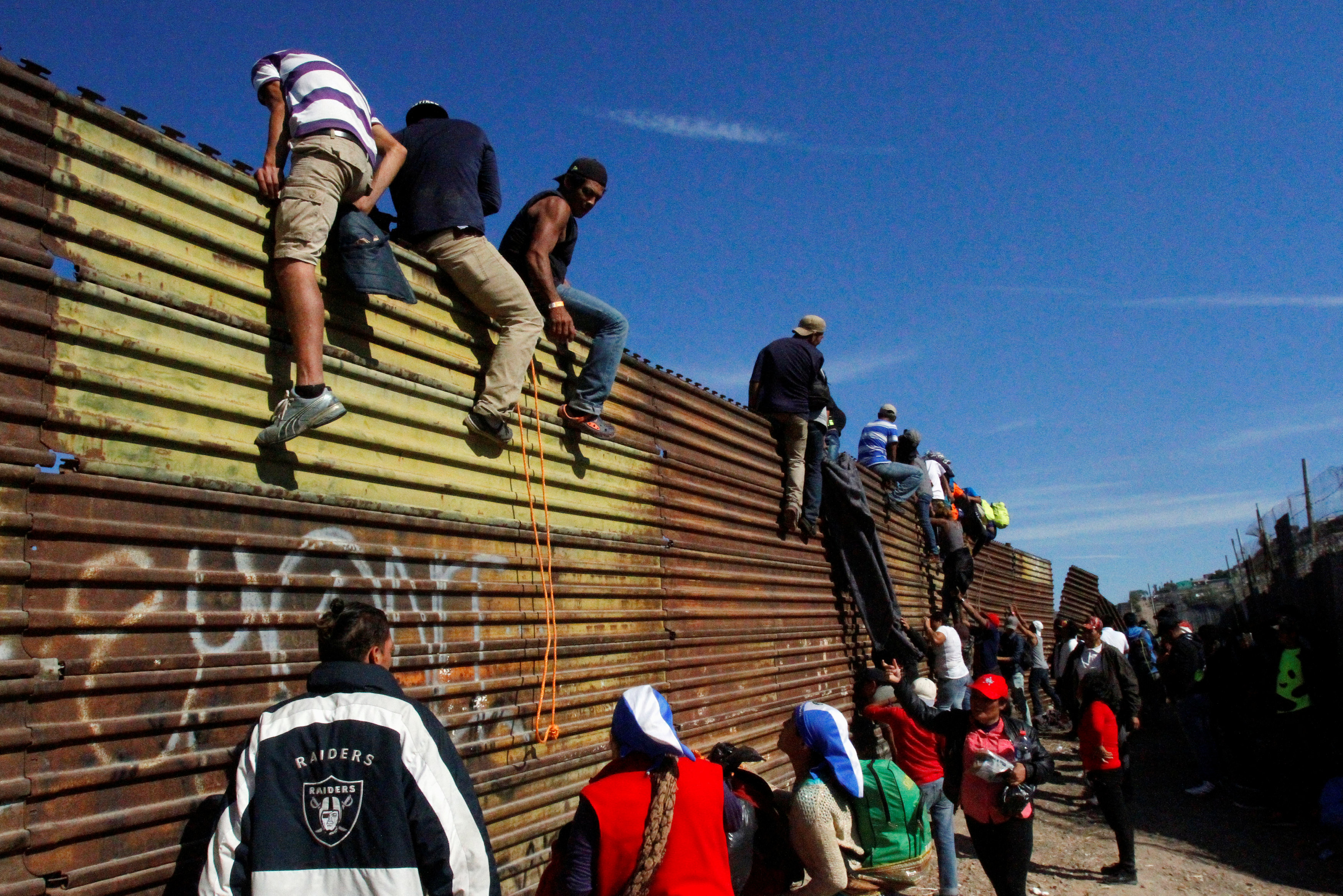 ▲▼移民攀上美墨邊界的圍牆，設法跨越到美國境內。（圖／路透）