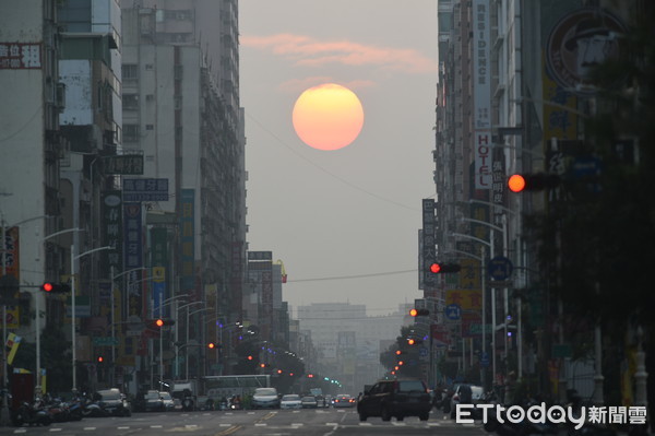 ▲高雄市一心路出現日出懸日，讓旭日光芒無法灑滿街道。（圖／張忠義提供）