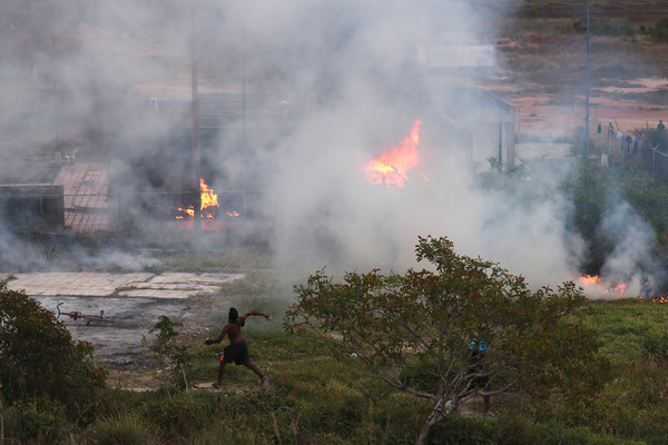 ▲▼一名男子在委內瑞拉與巴西的邊境處向軍方投擲石塊。（圖／路透）