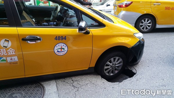 ▲北市中山區農安街路基疑遭雨水掏空產生下陷，一輛計程車陷入洞內動彈不得。（圖／記者張君豪翻攝）