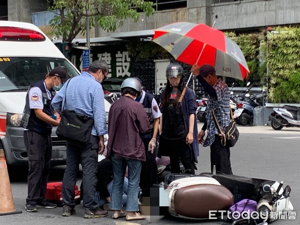 ▲一名女外送員疑似趕外送，騎機車擦撞前車受傷，路人幫忙撐傘             。（圖／記者吳奕靖攝）