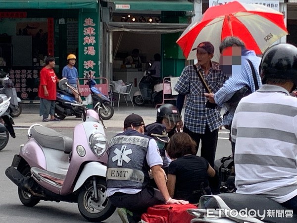 ▲一名女外送員疑似趕外送，騎機車擦撞前車受傷，路人幫忙撐傘             。（圖／記者吳奕靖攝）