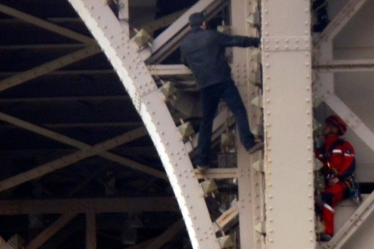 ▲法國黑衣男徒手爬上巴黎艾菲爾鐵塔（Eiffel Tower）。（圖／路透社）