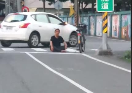 ▲▼一名男子坐在馬路中間，無視來往的車潮，讓人看了覺得很危險。（圖／翻攝臉書爆怨公社）