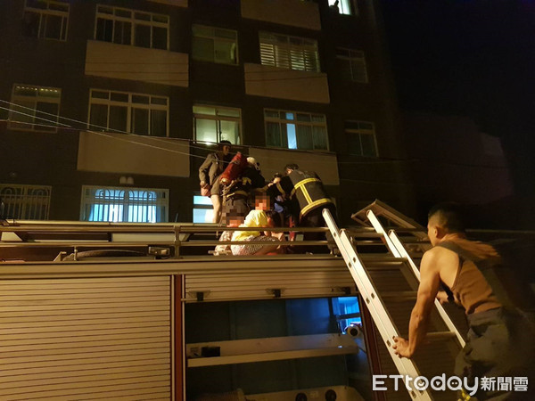 ▲竹南公寓馬達起火，濃煙往上竄，有民眾抱著嬰兒站在2樓採光罩等待救援。（圖／記者黃孟珍翻攝）