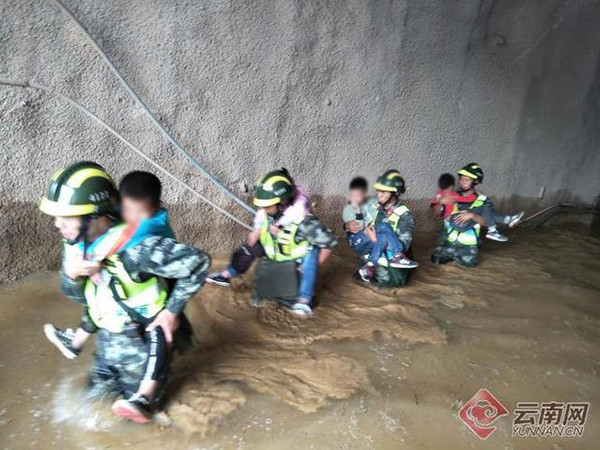 ▲救援官兵涉過及腰的積水，將孩童揹出隧道。（圖／翻攝雲南網）