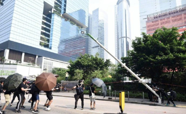 ▲香港示威者疑路燈燈柱設有人臉辨識功能，用電鋸毀壞再將它拉倒。（圖／翻攝自微薄）