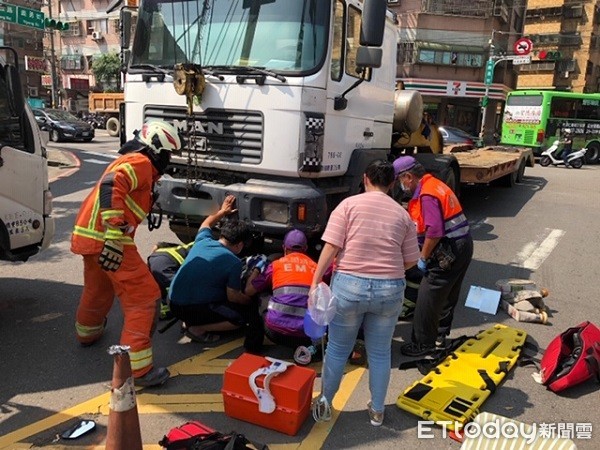 ▲救護人員正設法從曳引車輪胎下搶救騎士。（圖／桃園市消防局提供）