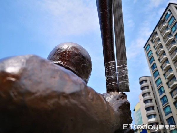 ▲高雄市立德棒球場門口《立德棒球小將》銅像的球棒跟國旗桿用膠帶黏一起             。（圖／記者吳奕靖攝）