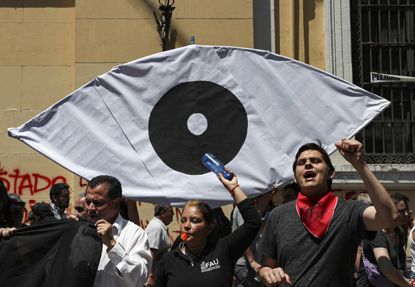 ▲一群示威者12日在首都聖地牙哥舉起一面畫著一隻眼睛的橫幅，抗議連日來有超過200人遭警方開槍射中眼睛。（圖／達志影像／美聯社） 