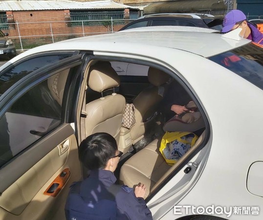 ▲桃園市八德警分局員警破窗救出車內男嬰，仔細查看男嬰是否無恙。（圖／記者沈繼昌翻攝）