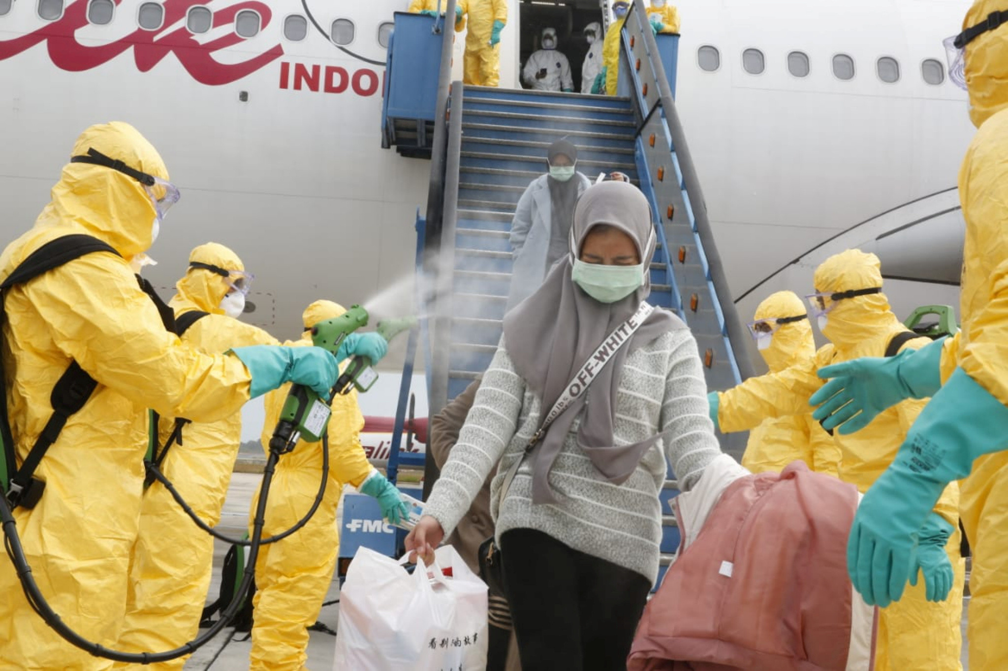 ▲▼印尼從中國撤回公民，乘客下機被消毒劑噴灑。（圖／路透）