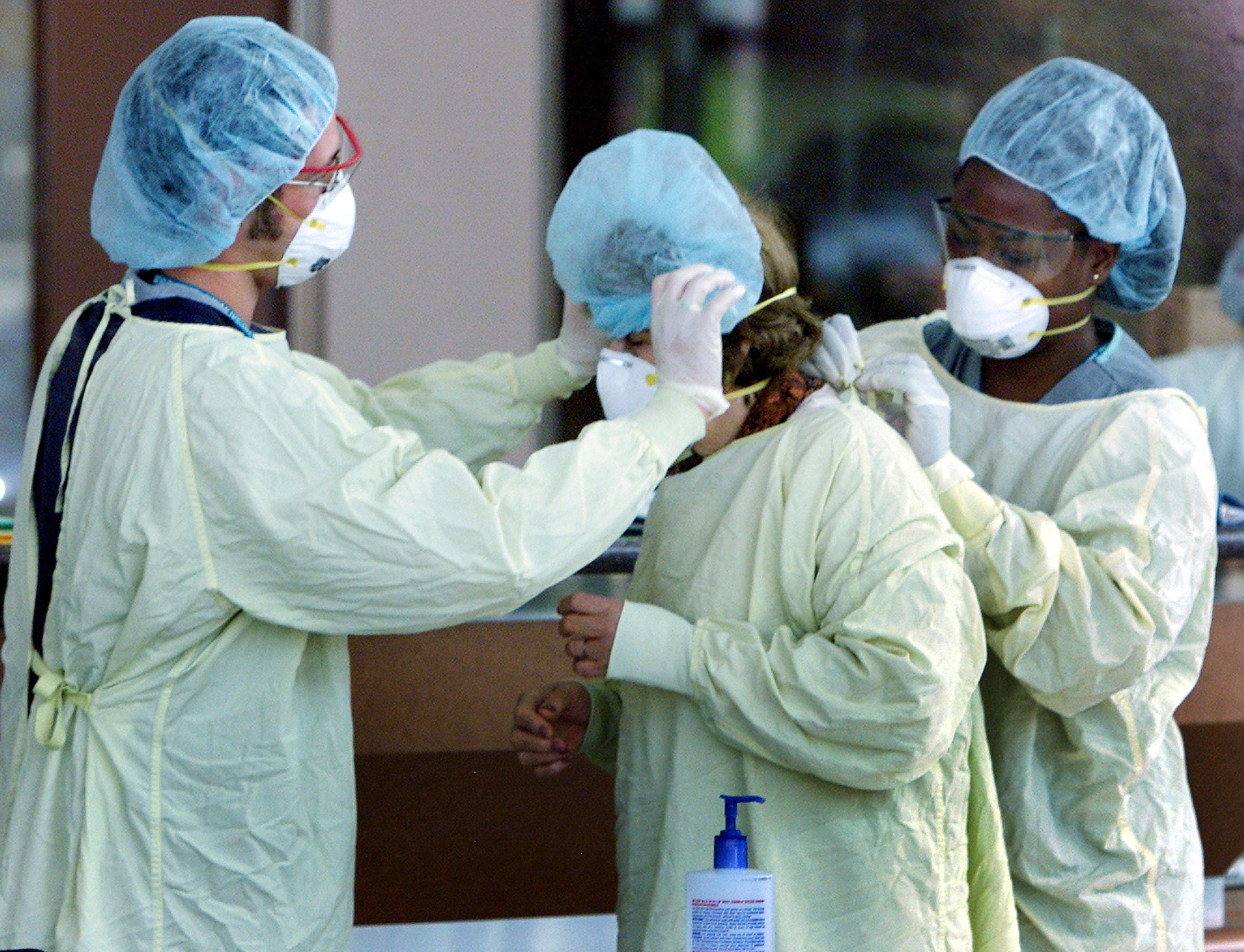 ▲加拿大多倫多北約克醫院（North York Hospital）的醫護人員為前來加護病房探病的民眾穿戴口罩與長袍，避免感染SARS。（圖／路透）