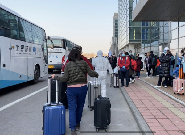 ▲入境北京旅客拉著行李，從機場搭車至分流點檢疫。（圖／翻攝北京日報）