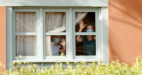 新冠肺炎肆虐全球，圖為西班牙阿德耶一處住宅，戴著口罩的人們透過窗戶往阿德耶海岸皇宮望去。（圖／路透社）