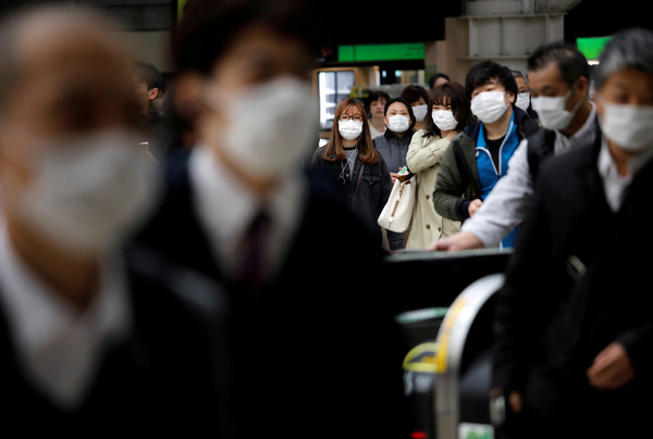 ▲日本進入緊急狀態後，乘客戴著口罩通勤。（圖／路透）