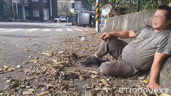 ▲小客車翻覆後，駕駛送醫救治，友人身上多處擦傷，自行困後驚魂未定的坐在路邊。（圖／記者黃孟珍翻攝）