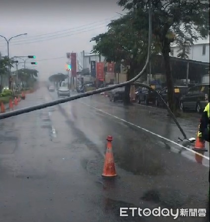 ▲台南市安南區北安路4段22日疑因豪雨造成路燈倒塌，路燈橫倒在道路，僅剩外側車道可通行，台南市警三分局冒雨維持交通，並合力將燈桿移至分隔島旁。（圖／記者林悅翻攝，下同）