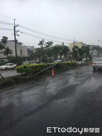 ▲台南市安南區北安路4段22日疑因豪雨造成路燈倒塌，路燈橫倒在道路，僅剩外側車道可通行，台南市警三分局冒雨維持交通，並合力將燈桿移至分隔島旁。（圖／記者林悅翻攝，下同）