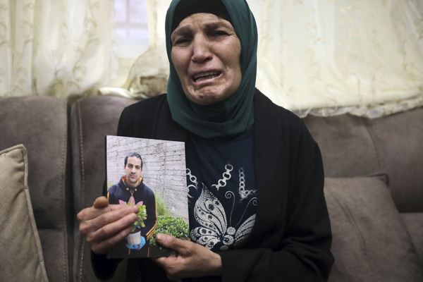 自閉症男子哈拉克（Iyad Halak）遭警察開槍致死，他的母親傷心地拿著照片控訴警方執法過當。（圖／達志影像／美聯社）