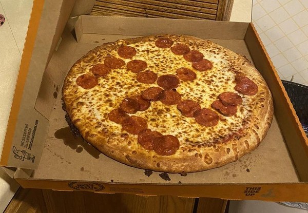 一對夫妻買到披薩，上頭的臘腸片被店員惡作劇擺成「卍」字。（翻攝自@LaskaMisty推特）
