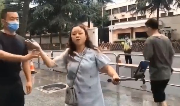 ▲大媽再領事館前唱歌，被警察制止小碎步離開。（圖／翻攝自微博）