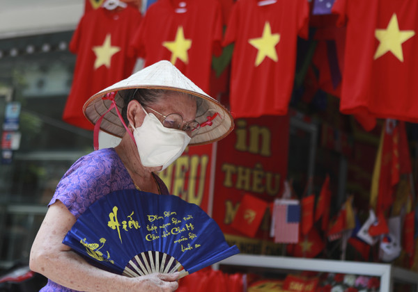 ▲越南新冠疫出現大反彈。圖為一名戴著口罩的女子，從一排國旗T恤前面走過。(圖／達志影像／美聯社)