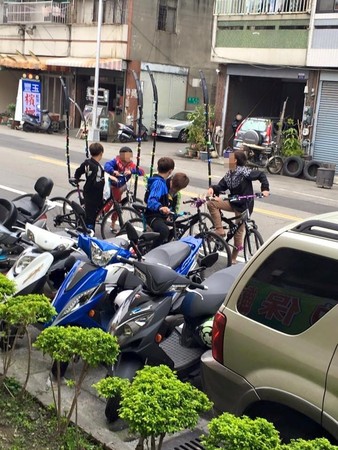 ▲4年多前，網友路邊直擊，一群小朋友腳踏車後方有根高聳長竿。（圖／翻攝自爆料公社）