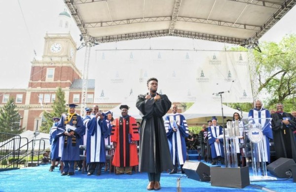 查德維克博斯曼（中）在2018年，受邀回母校霍華德大學畢業典禮致詞，擺出「瓦干達萬歲」的手勢。（翻攝自Howard University官方臉書）