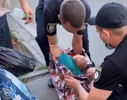 ▲▼烏克蘭一位婦女將小男嬰裹著外套裝在購物袋裡，大搖大擺走在路上，被警方盤查。（圖／翻攝自YouTube／@24TVPROD）