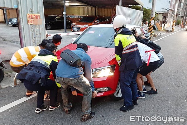 ▲桃園市游姓男子29日上午開車載家人參訪桃園地景藝術節展品，卻不慎撞上路旁電線桿，員警請路人協助合力將故障車頭抬起。（圖／記者沈繼昌翻攝）