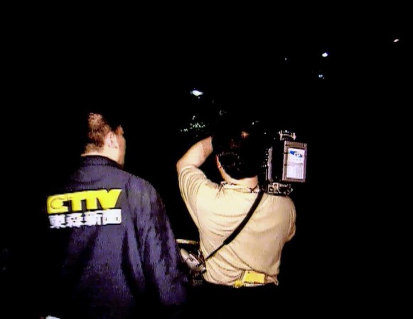 刑警施俊雄（左）扮成電視台記者，與扛著攝影機的正牌記者（右）準備進入封鎖現場談判。（東森新聞提供）
