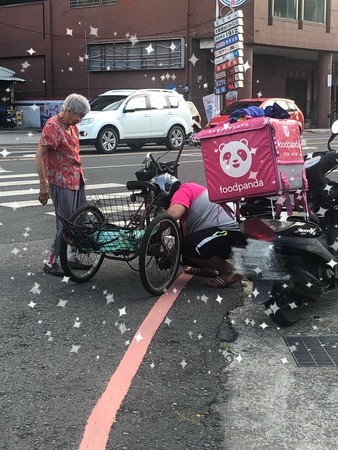 ▲外送員將車停在路邊，蹲下替阿婆修三輪車 。（圖／翻攝自Facebook／我是新營人）