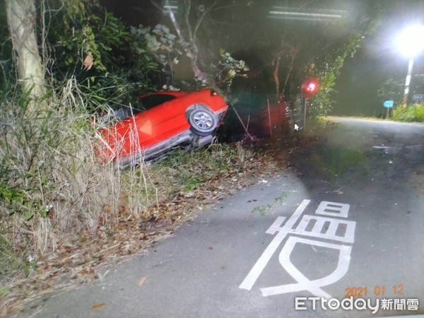 ▲台南新化區知義里附近有１台紅色自小客車衝出路面卡在邊坡，消防人員救出車內47歲陳姓爛醉女子，警方懷疑陳女酒駕肇事，正調監視影像追查中。（圖／記者林悅攝）