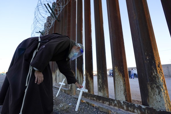 ▲▼神父在美墨邊境圍牆邊放上十字架，紀念那些在穿越邊境過程中喪生的移民。（圖／達志影像／美聯社）